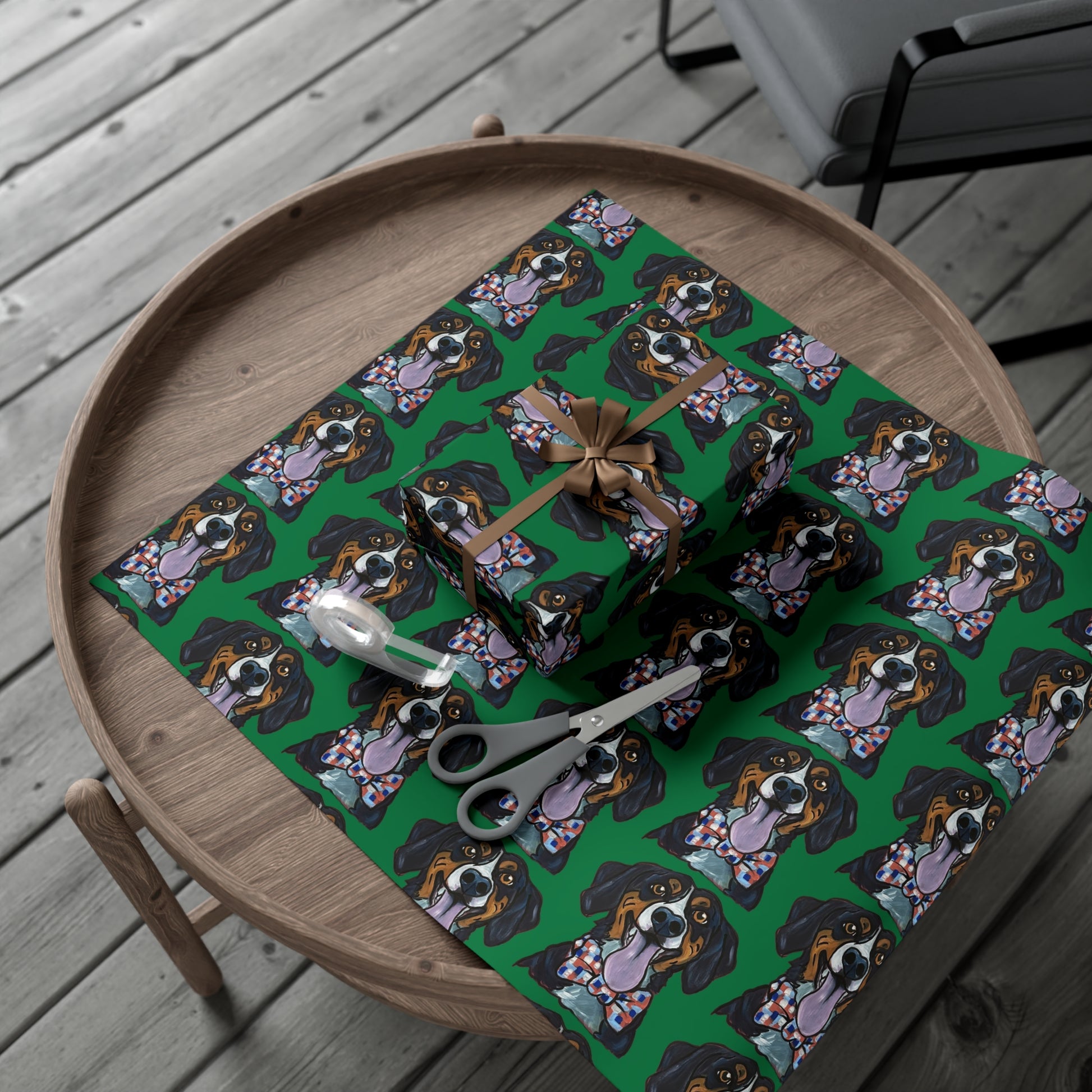 Gift boxes wrapped in green wrapping paper featuring custom hand drawn dog caricature portrait,  scissors, and tape on a wood table